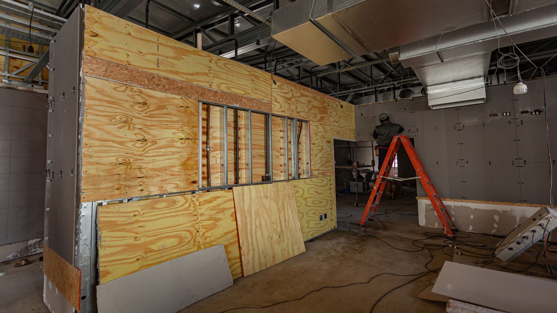 Inside of a building under construction with a man in a ladder